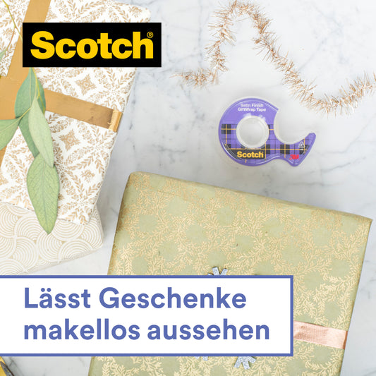Das Scotch® Geschenk-Klebeband im Handabroller CAT 15 (19 mm x 15 m) von 3M Deutschland GmbH liegt auf hellem Untergrund neben zwei schön verpackten Geschenken mit Goldband und Zweig. Text: "Lässt Geschenke makellos aussehen.