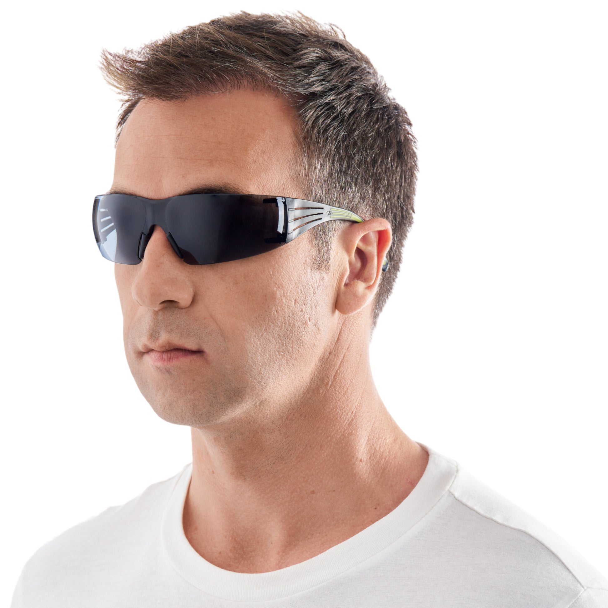 Ein Mann mit kurzen braunen Haaren modelliert die 3M™ SecureFit™ Schutzbrille 400 von 3M Deutschland GmbH. Er trägt eine schwarze Rundum-Schutzbrille und ein weißes T-Shirt vor einem schlichten weißen Hintergrund.