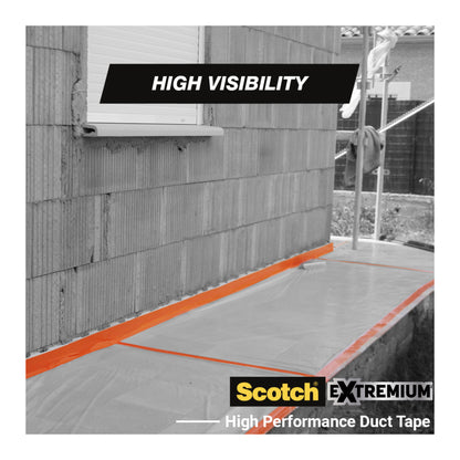 Ein Streifen orangefarbenes Scotch® High Visibility Klebeband, 25 m x 48 mm von 3M Deutschland GmbH, sichert eine klare Kunststofffolie am Sockel eines Backsteinhauses. Die Worte "High Visibility" und "Scotch High Visibility Klebeband" sind sichtbar.