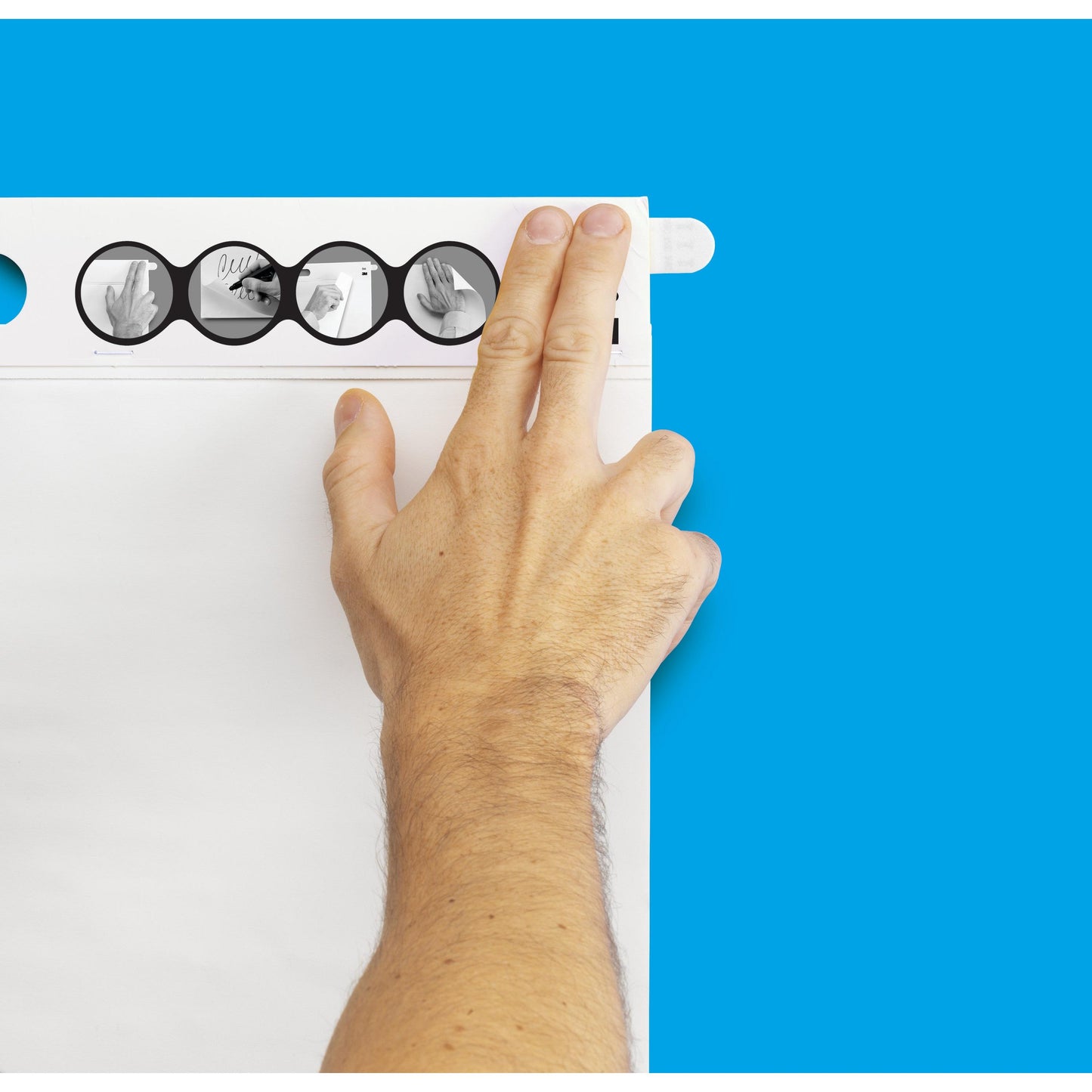 En person fastgør et ark på et flipchart med blå baggrund ved hjælp af Post-it® Super Sticky selvklæbende mødechart/flipchart 566 (58,4 x 50,8 cm, 20 ark, 2 blokke) fra 3M Deutschland GmbH med Command™-strimler og illustreret vejledning.