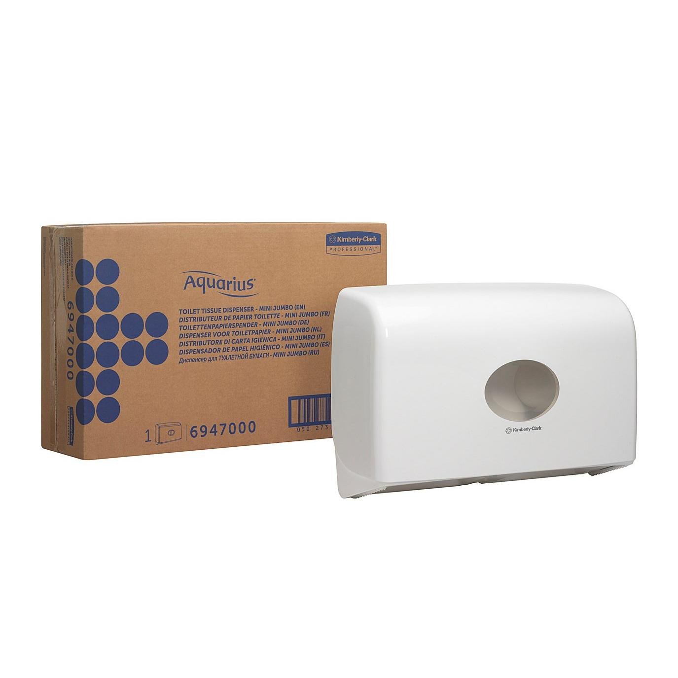 En hvid Aquarius™ dobbeltrolledispenser til Jumbo-Toiletpapir Mini fra Kimberly-Clark GmbH er monteret på væggen ved siden af en brun kasse med teksten "Aquarius" og blå punktgrafik og produktinformation.