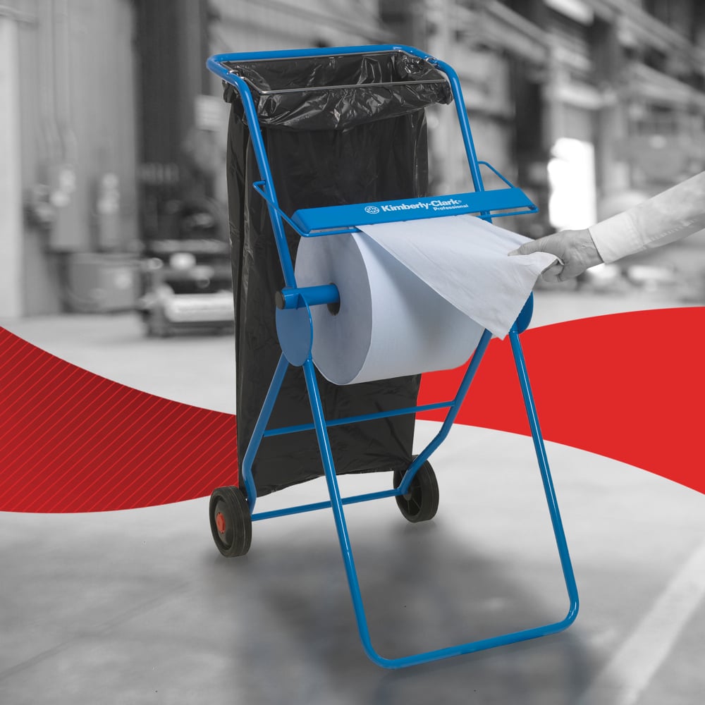 Eine Person benutzt ein WypAll® L30 Papierwischtuch von Kimberly-Clark GmbH von der extra breiten Großrolle auf einem blauen Spender mit Müllsack im Industrieumfeld-perfekt für industrielle Reinigungsaufgaben.