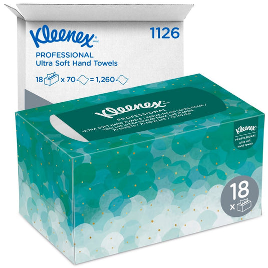 En æske Kleenex® Ultra™ Interfold-håndklæder (hvide, mellemstore, 70 stk.) fra Kimberly-Clark GmbH er afbildet foran en hvid forsendelseskasse med påskriften »1126« og »18 x 70 = 1.260«, som indeholder 18 hygiejnepakker.