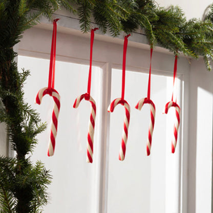 Fünf rote und weiße Zuckerstangen hängen an einem weißen Türrahmen mit grüner Tannengirlande. Die Command™ Dekorations-Clips, transparent, mit transparenten Strips von 3M Deutschland GmbH machen das Dekorieren zu einem Kinderspiel. Sonnenlicht verleiht der Dekoration eine festliche Note.