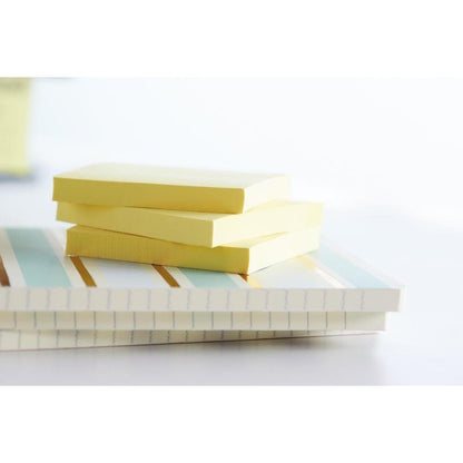 Tre stakke Post-it® genbrugssedler (38 mm x 51 mm, 100 ark, 100% PEFC) fra 3M Deutschland GmbH ligger på to lukkede, stribede og linjerede notesbøger foran en blidt sløret baggrund.