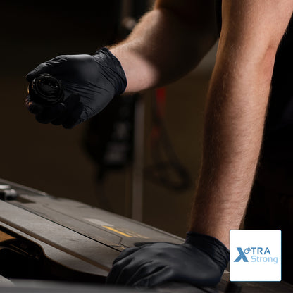 Eine Person, die ARNOMED NITRIL BLACK XTRA STRONG Einmalhandschuhe aus Nitril von ARNOWA GmbH in Schwarz trägt, arbeitet am Auto. Im Bild ist das "XTRA Strong" Logo sichtbar.