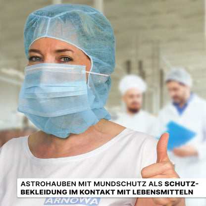 En kvinde i hvid, der bærer ARNOMED COVER PP-ASTROHAUBE MED 2-LAGS MUNDBESKYTTELSE fra ARNOWA GmbH, viser tommelfingeren op; bag hende kan to personer i hvide uniformer ses sløret. Den tyske tekst handler om beskyttelsestøj til kontakt med fødevarer.
