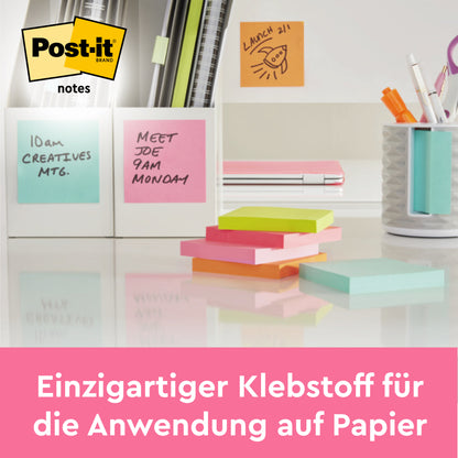 Et skrivebord med 3M Deutschland GmbH Post-it® Notes (76 mm x 127 mm, 100 ark/blok, 100% PEFC), pastelfarvede og stablet, samt penne i en holder og klisternoter på et whiteboard med påmindelsesfunktion. Den tyske tekst fremhæver den unikke klæber til papir.