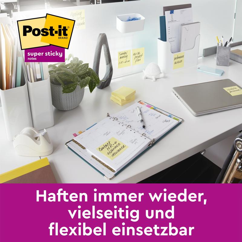 Et moderne kontorbord med bærbar computer, planlægger, plante, tape dispenser og kontorartikler viser flere gule 3M Deutschland GmbH Post-it® Super Sticky Notes (76 mm x 76 mm, 45 ark/blok, 100% PEFC), der er fastgjort til genstande. Tysk tekst i et lilla banner nedenunder.