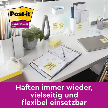 Et moderne kontorbord med bærbar computer, planlægger, plante, tape dispenser og kontorartikler viser flere gule 3M Deutschland GmbH Post-it® Super Sticky Notes (76 mm x 76 mm, 45 ark/blok, 100% PEFC), der er fastgjort til genstande. Tysk tekst i et lilla banner nedenunder.