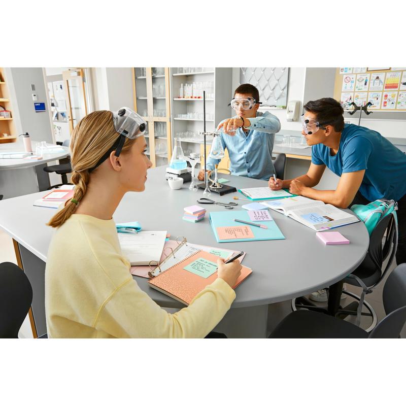 Tre studerende med beskyttelsesbriller sidder ved et laboratoriebord med lærebøger, laboratorieudstyr og 3M Deutschland GmbH Post-it® Super Sticky Notes (76 mm x 127 mm, 90 ark/blok, 100% PEFC) og tager noter, mens en justerer en klemme og de andre observerer opmærksomt.