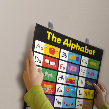 En person viser en levende alfabettavle med billedbogstaver, der midlertidigt er fastgjort til en glat væg med 3M Deutschland GmbH Scotch-FIX™ Aftagelige Monteringsfirkanter 108-ST64-P, 12,7 mm x 12,7 mm, og nemt kan fjernes igen. Pakken indeholder 64 stk.