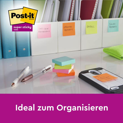 Et skrivebord med mapper, mærket med Post-it® Super Sticky Notes, 76 mm x 76 mm, 45 ark/blok, fra 3M Deutschland GmbH. Der ses stablede noter, penne, en telefon og kontorartikler; logo i hjørnet. Tekst: "Ideel til organisering.