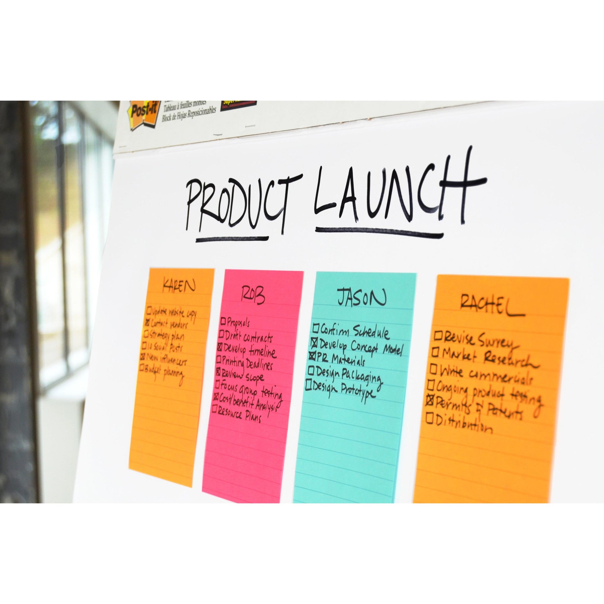 Ein Whiteboard mit der Aufschrift "Product Launch" am oberen Rand enthält vier farbcodierte Aufgabenlisten - Karen, Riz, Jason und Rachel - mit Checklisten, die auf 3M Deutschland GmbH Post-it® Super Sticky Notes im Großformat, liniert, geschrieben sind.