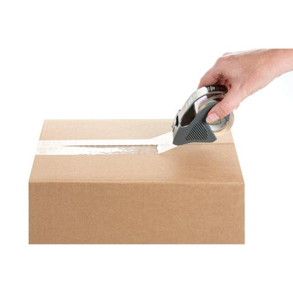 En hånd lukker en brun kasse over den øverste søm med Scotch® Box Lock™ emballagetape 48 mm x 20,3 m fra 3M Deutschland GmbH med en tape dispenser, alt sammen foran en hvid baggrund.