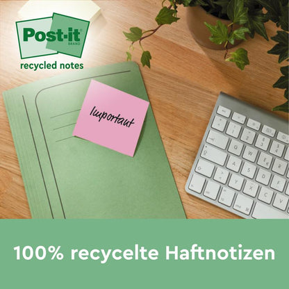 En grøn mappe med en lyserød Post-it® genbrugsseddel fra 3M Deutschland GmbH (38 mm x 51 mm, 100 ark/blok, 100% PEFC) ligger på et træbord ved siden af et hvidt tastatur og en potteplante.