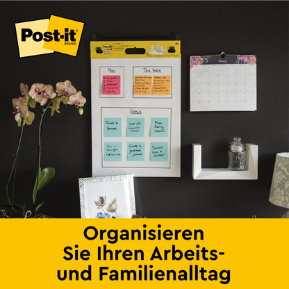 Eine Bürowand zeigt eine Post-it® Super Sticky Recycling Meeting Chart 559RP (63.5x76.2cm, 30 Blatt, 2 Blöcke), farbige Notizen, Kalender und Pflanzen. Text: "Organisieren Sie Ihren Arbeits- und Familienalltag." Von 3M Deutschland GmbH.
