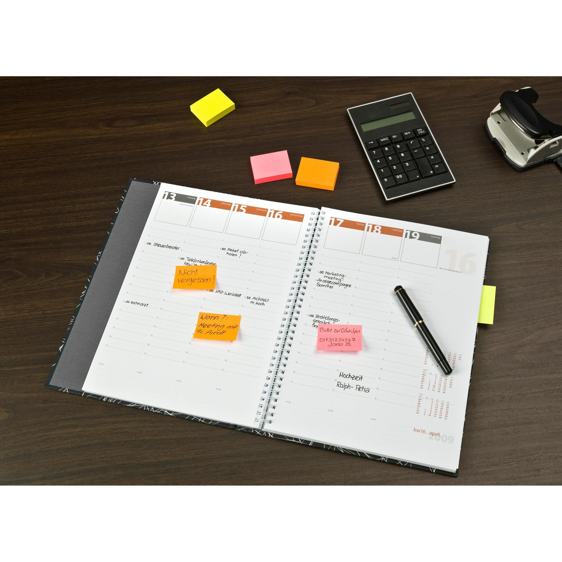 Ein offener Planer mit handschriftlichen Notizen und 3M Deutschland GmbH Post-it® Notes in verschiedenen Neonfarben (38mm x 51mm, 3+1 Pack, PEFC) liegt auf einem Holztisch neben Stift, Taschenrechner und Klebebandabroller.