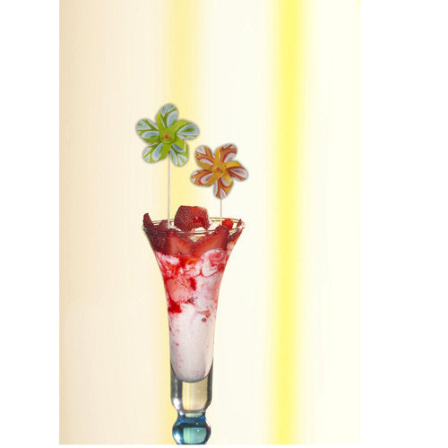 Et højt glas indeholder en lyserød-hvid dessert, toppet med jordbærsauce og en PAPSTAR dekoration-picker "vindmølle" (17,5 cm, farvesorteret), der legende beriger festdekorationen. Sættet fra PAPSTAR GmbH indeholder 50 pickere i en papbakke.