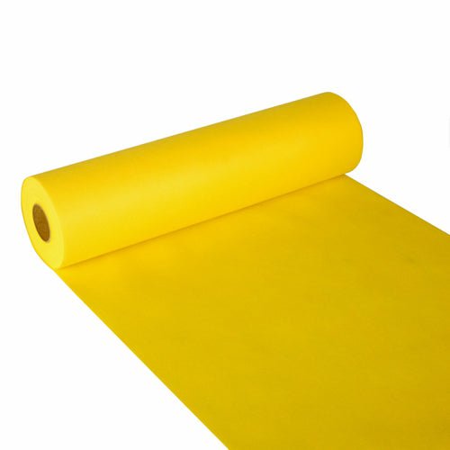En rulle Starpak bordløber, stoflignende fleece „Soft Selection“ (24 m x 40 cm), i lysende gul, er bredt ud på en hvid overflade og viser det bløde papir, der stikker ud fra den cylindriske Starpak-rulle.