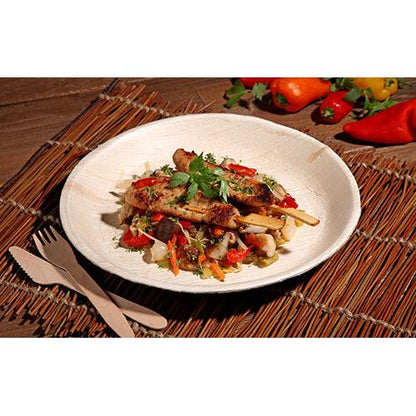 Grillet kødspyd med blandede grøntsager og krydderurter serveres på en PAPSTAR 25 tallerken, palmeblad "pure" rund fra PAPSTAR GmbH, med miljøvenligt engangsservice og farverige peberfrugter og grøntsager i baggrunden.