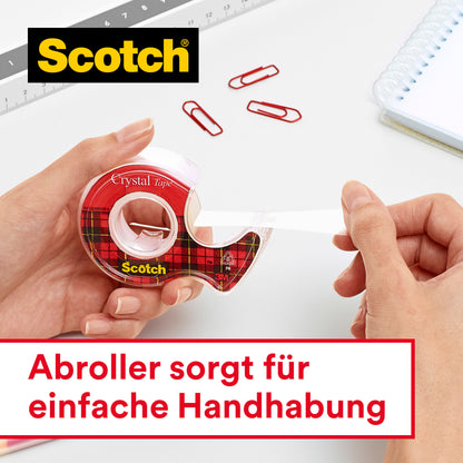 Jemand zieht transparentes Scotch® Crystal Klebeband 6-1915R3/2 aus einem Spender. In der Nähe liegen rote Büroklammern, ein Lineal und ein Notizbuch. Deutscher Text: "Abroller sorgt für einfache Handhabung." Marke: 3M Deutschland GmbH.