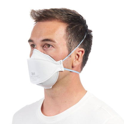 En mand i en enkel hvid skjorte bærer en 3M™ Aura™ Komfort-partikelmaske 9320+ FFP2 åndedrætsværn uden ventil fra 3M Deutschland GmbH, med to hovedbånd og let vendt mod venstre.