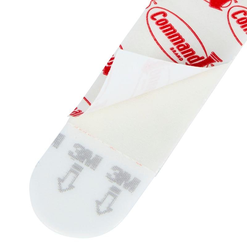 Et nærbillede af et Multipack Command™ Strips, 17200 fra 3M Deutschland GmbH med delvist fjernet beskyttelsesfolie, der viser klæbeoverfladen og den trykte vejledning til ophængning af billeder - de perfekte klæbestrips uden boring.