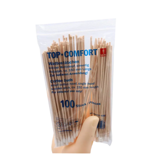 Eine Hand hält eine durchsichtige Plastikpackung mit AMPri TOP-COMFORT Wattestäbchen, perfekt für die Krankenhauspflege. Die Packung enthält 100 Einweg-Wattestäbchen mit Naturholzstäbchen, Produktdetails sind sowohl auf Deutsch als auch auf Englisch angegeben.