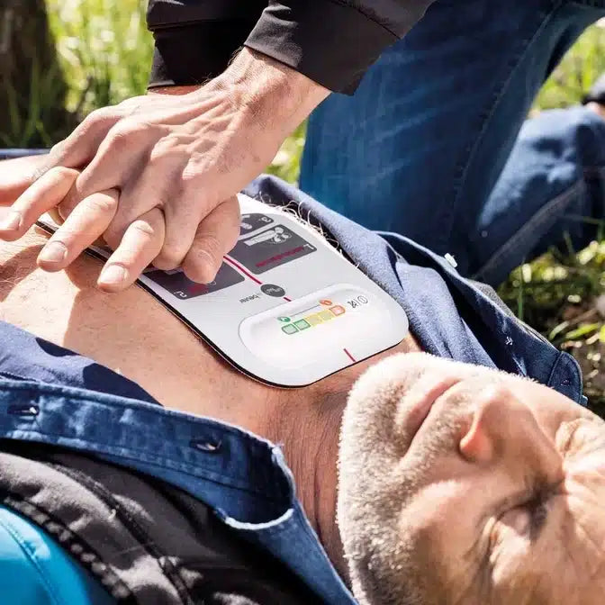 En voksen mand modtager hjertemassage med innotas Beurer LifePad® genoplivningshjælp (udgået vare, 1 stk.), mens en AED-pad er placeret på hans nøgne bryst for effektiv førstehjælp.