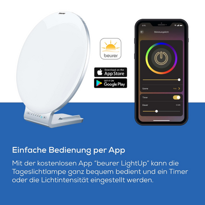Beurer dagslyslampe TL 100 (udgået artikel) fra Beurer GmbH er afbildet i hvid med 10.000 lux ved siden af en smartphone med LightUp-appen, der er kompatibel via App Store-logoer med iOS og Android; tysk tekst fremhæver app-baseret kontrol.