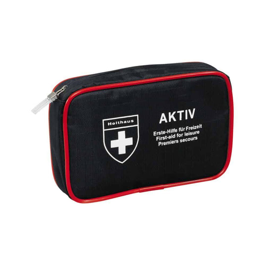 Et kompakt, sort førstehjælpssæt med røde kanter og lynlås, et hvidt korslogo og teksterne »Holthaus Medical AKTIV« og »Erste-Hilfe für Freizeit / First-aid for Leisure / Premiers secours« på forsiden. Perfekt til rejser og til brug derhjemme.