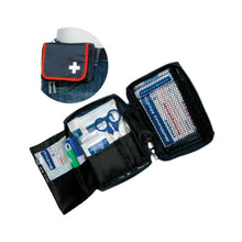 Die Holthaus Medical Verbandtasche TRAVEL blau/rot von Holthaus Medical GmbH & Co. KG ist geöffnet abgebildet und mit medizinischem Bedarfsmaterial wie Verbandsmaterial, Scheren und antiseptischen Tüchern gefüllt. Der Einband ist mit einem weißen Kreuzsymbol und einer Gürtelbefestigung versehen. Ein eingefügtes Bild zeigt das Set an einem Jeansgürtel befestigt.
