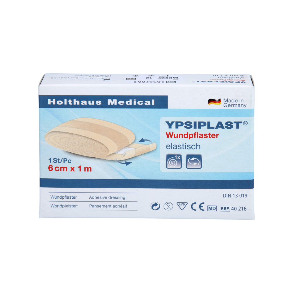 Billedet viser en pakke Holthaus Ypsiplast® sårplaster, elastisk - 6 cm x 1 m fra Holthaus Medical GmbH & Co. KG. Æsken indeholder et enkelt stykke elastisk plaster og viser, at det er fremstillet i Tyskland af åndbart stof. Derudover er der flere symboler og produktspecifikationer at se.
