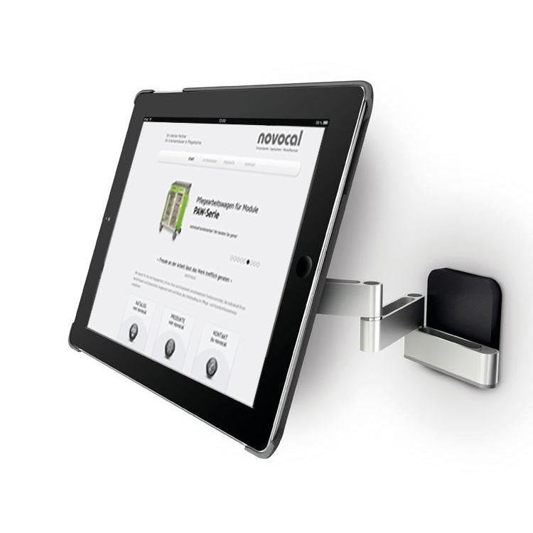 En Novocal-tabletholder version 1 (til tablets 7-12 tommer, svingbar op til 180°) er monteret på en sølvfarvet vægbeslag med svingarm; på tabletten ses en hjemmeside med "novocal" som overskrift.