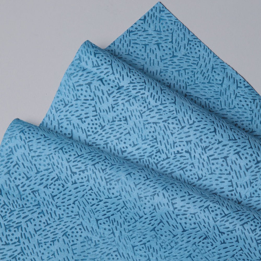 Nærbillede af foldede Kimtech® procesrenseservietter (Kimberly-Clark GmbH) i blå, BRAG™ boks - 160 ark, med geometrisk streg- og prikkemønster. Ideel til krævende industriel rengøring. Udstillet på en lysegrå overflade.
