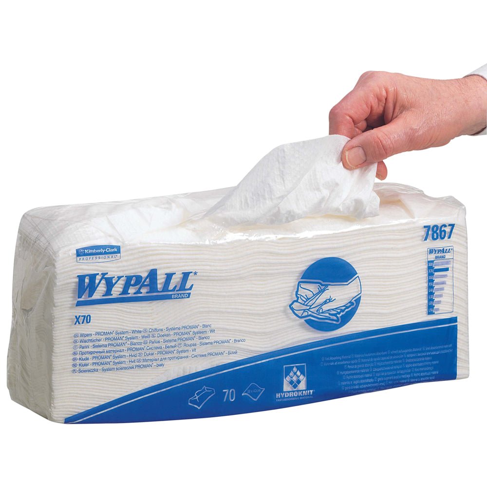 En hånd trækker en WypAll® X70 viskestykke ud af en rektangulær emballage med teksten "WypAll® X70" (70 klude, 6 poser/kasse) fra Kimberly-Clark GmbH. Den for det meste hvide emballage er forsynet med blå tekst og grafik til industriel rengøring.