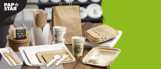 Werbebanner der Marke PAPSTAR mit nachhaltigem Einweggeschirr: Pappbecher, Pappteller, Papiertragetaschen, Holzbesteck, Schalen und Verpackungen aus Karton, Papier und Palmblatt. Hintergrund in Grün und Holzoptik.