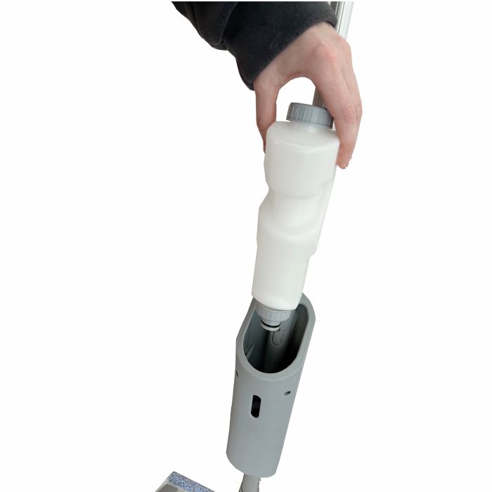 En person indsætter en hvid rengøringsløsningsflaske i håndtaget på Arcora Ultra Mobile Spray Mop System fra Arcora International GmbH på hvid baggrund.