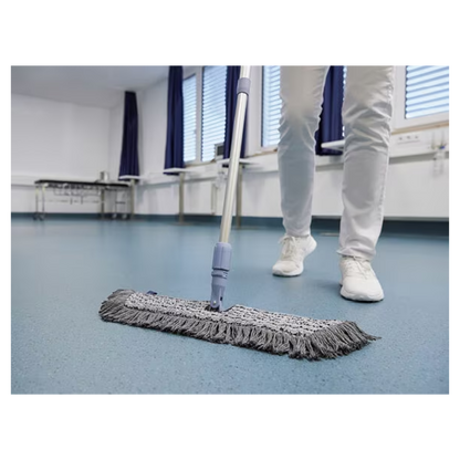 Eine Person in weißen Schuhen und Hosen wischt mit einem Vileda GmbH Professional Swep Duo r-MicroCombi Mop - 50 cm einen blauen Boden in einem Raum mit geschlossenen Jalousien und blauen Vorhängen. In der Nähe stehen ein Klapptisch und unter den Fenstern ein Heizkörper.