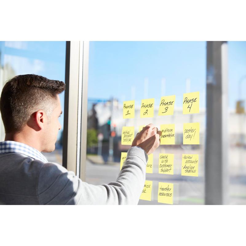 En mand bruger Post-it® Super Sticky Notes (76mm x 127mm, 90 ark/blok, 100% PEFC) fra 3M Deutschland GmbH til at organisere projektfaser og opgaver på et vindue og planlægge en arbejdsgang i dagslys.