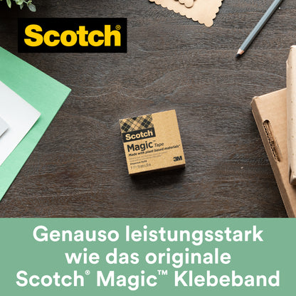 Eine Schachtel Scotch® Magic™ Klebeband von 3M Deutschland GmbH (19 mm x 33 m, 9 Rollen/Packung, mit 66 % pflanzlichem Klebstoff) liegt auf einem Holztisch neben grünem und weißem Papier, einem Notizbuch und einem Stift - perfekt für umweltbewussten Bürobedarf.
