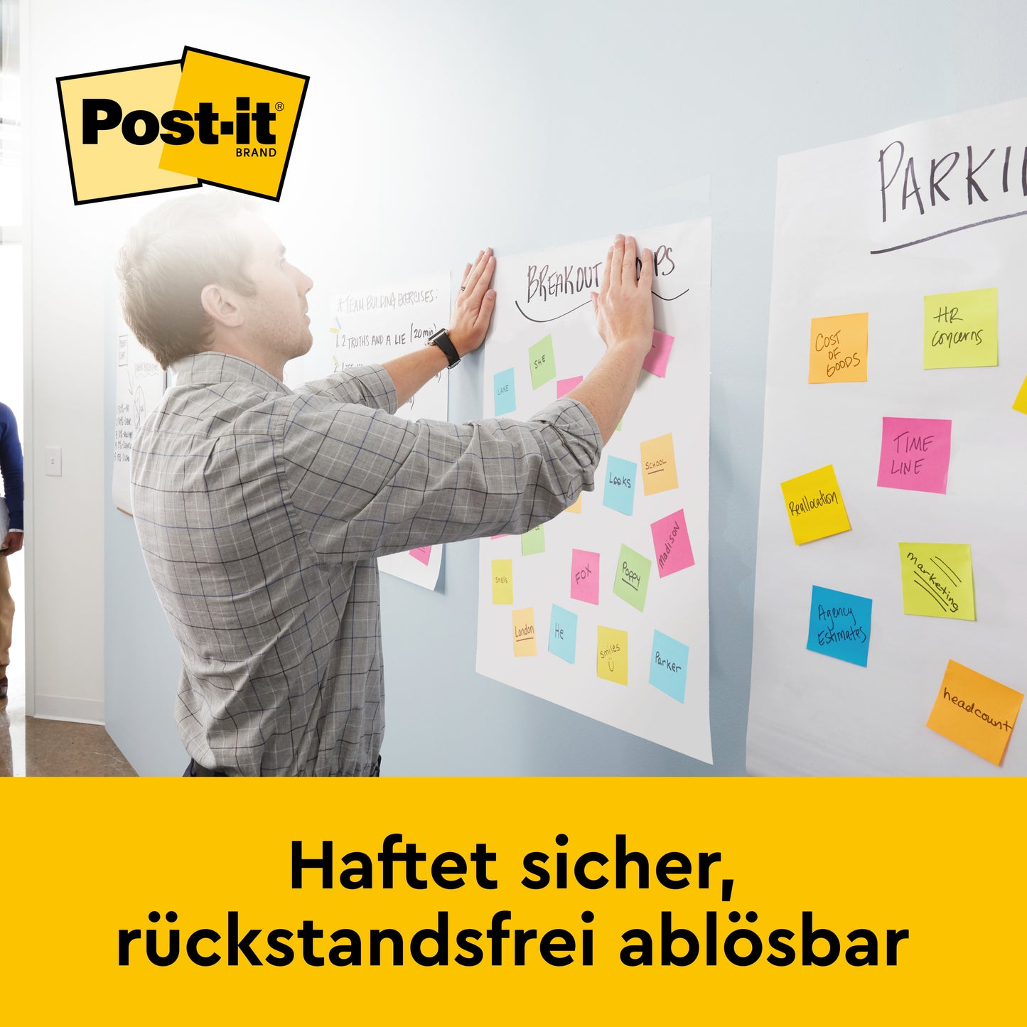 En mand presser et papirark med farverige Post-it-sedler mod en væg og præsenterer dermed 3M Deutschland GmbH Post-it® Super Sticky selvklæbende mødechart/flipchart til vægmontering 566 (58,4 x 50,8 cm, 20 ark, 2 blokke, inkl. Command™-strimler).