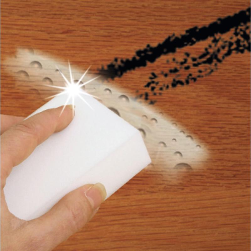 En hånd bruger Scotch-Brite® Magic Pad fra 3M Deutschland GmbH til at fjerne sorte pletter og vanddråber fra en træoverflade og opnå en ren, skinnende overflade.