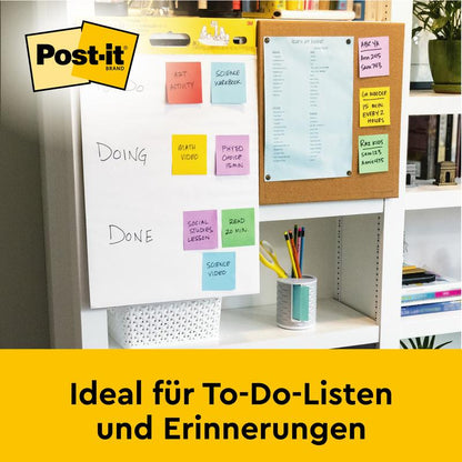 På skrivebordet står et Post-it® Super Sticky selvklæbende mødeplanchart/flipchart fra 3M Deutschland GmbH (hvid, 63,5x76,2cm), perfekt til to-do-lister & påmindelser. I baggrunden: en opslagstavle med blåt papir.