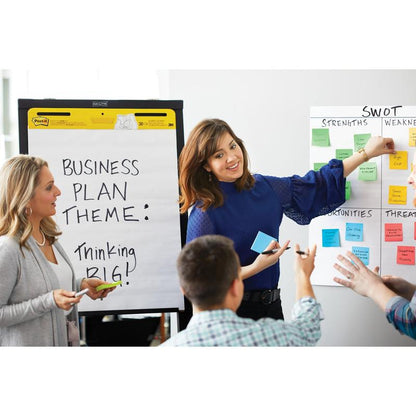 Under et forretningsmøde hos 3M Deutschland GmbH peger en kvinde på en SWOT-analyse, mens en anden holder en markør ved siden af et flipchart med teksten "Business Plan Theme" holder: Thinking BIG!" med Post-it® Super Sticky Notes, 76 mm x 127 mm, 90 ark/blok, 100% PEFC.